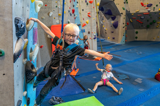child rock climbing, small kid with glasses rock climbing happy